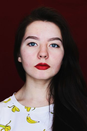 Portrait of beautiful young woman against maroon wall
