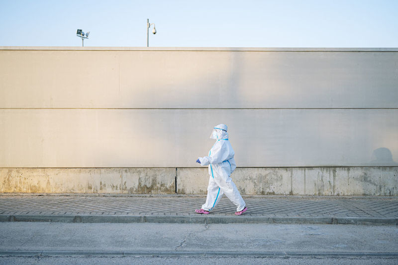 Nurse wearing protective wear while walking on footpath in city