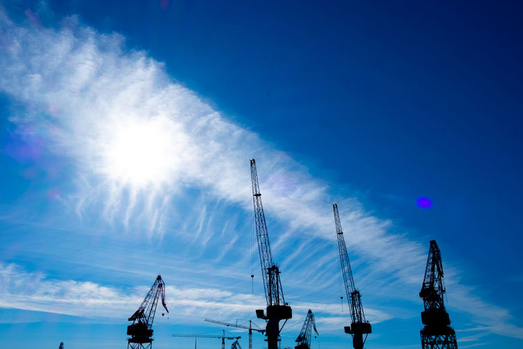 Low angle view of silhouette cranes against sky