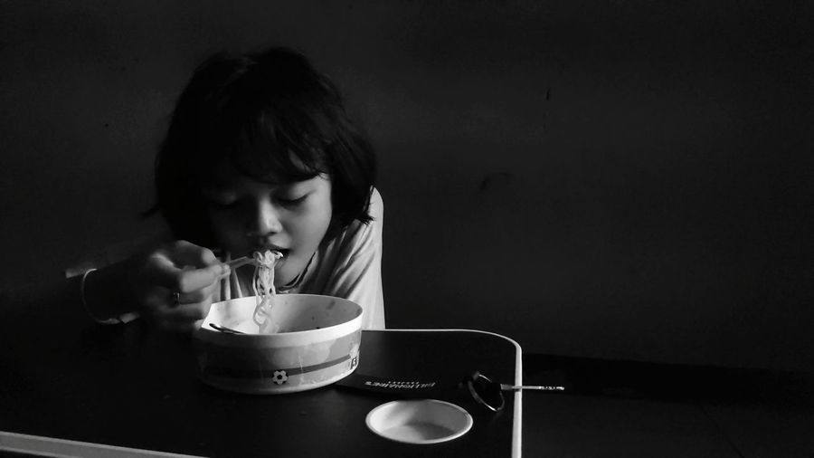 Little girl eating instant noodles in the morning