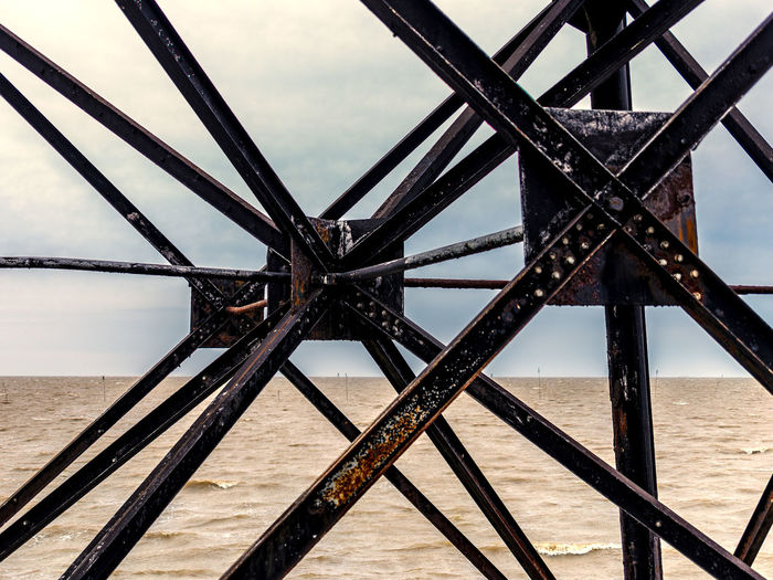 Low angle view of metal bridge over sea