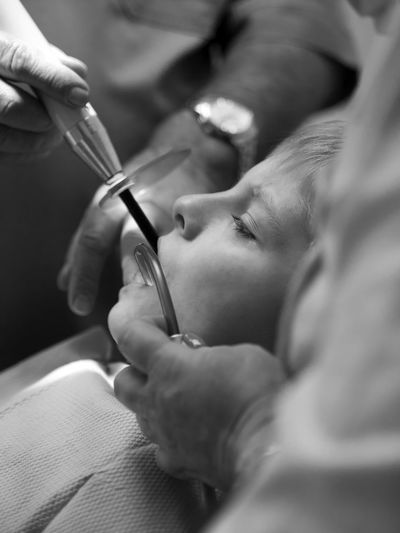 Close-up of dentist filling teeth of boy at clinic