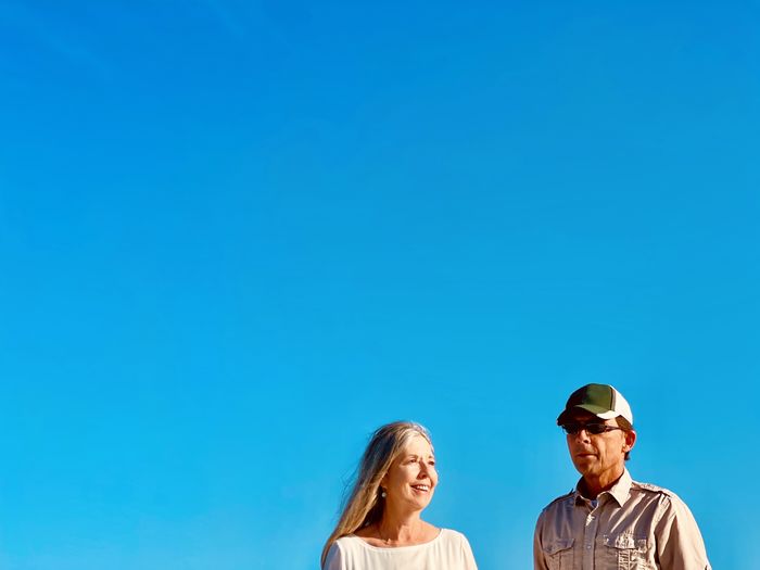 Active senior couple walking together against blue sky. front view shoulders up and copy space.