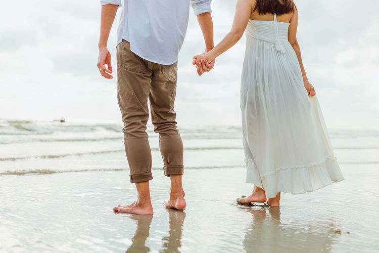 Low section of couple standing on beach