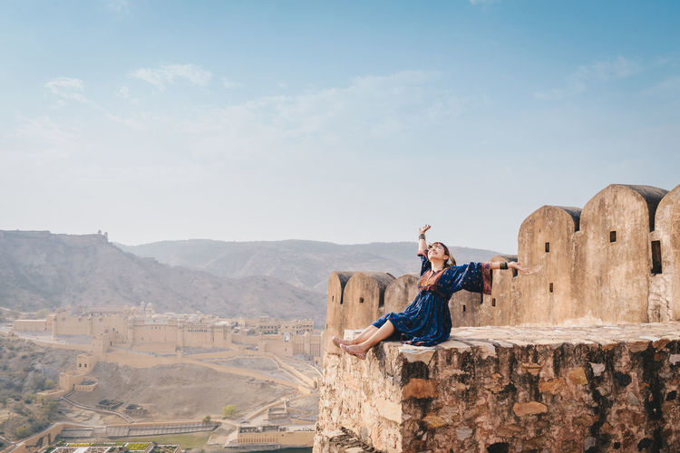 Woman sitting at fort against mountains