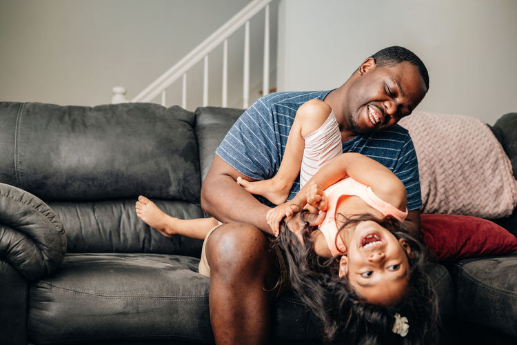 Father and kids at home playing on couch, african american or black father with his children