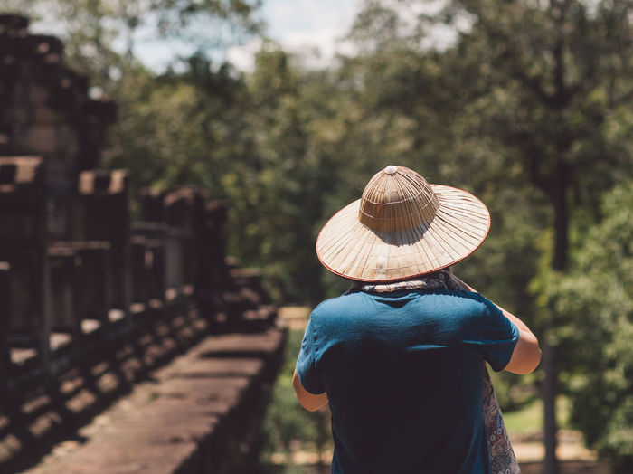 Rear view of man wearing hat standing in park during sunny day