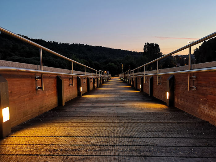 Empty footbridge against clear sky at sunset