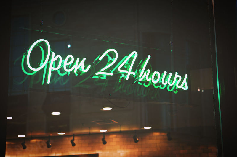 Open 24 hours green neon sign illuminated at night