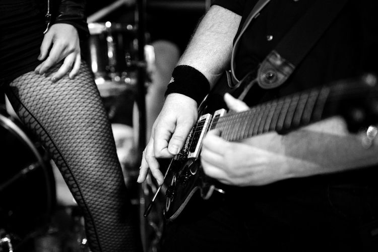 Midsection of man playing guitar by woman wearing stockings