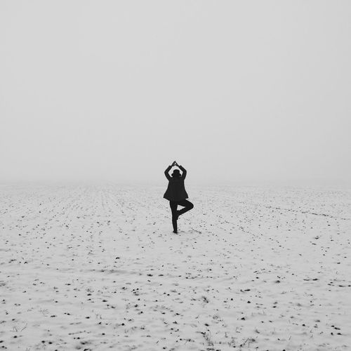 Rear view of woman doing yoga in snowy field