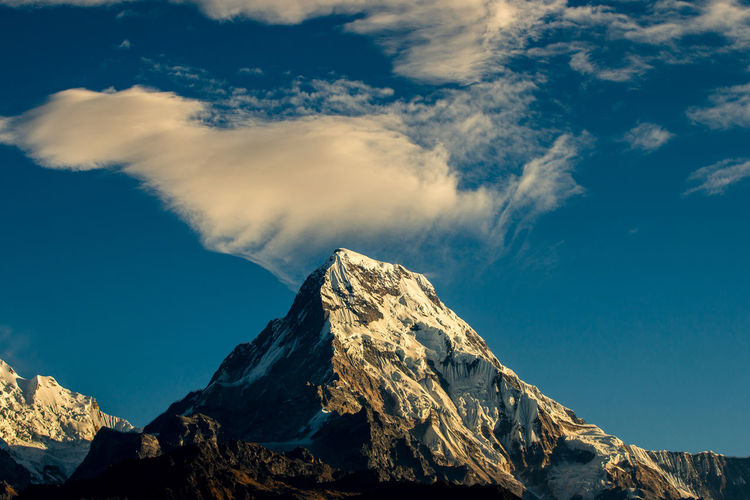 Low angle view of snowcapped mountains against blue sky