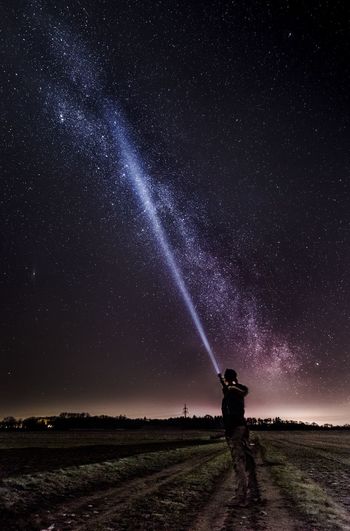 Mana with flashlight under star field at night