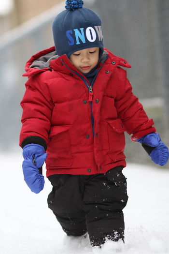 Cute boy walking on snow covered land during winter