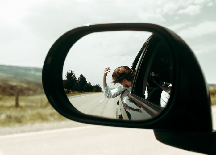 Reflection of woman on side-view mirror of car