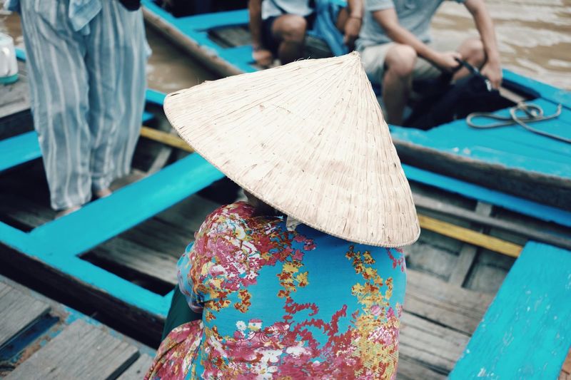 Rear view of woman wearing asian style conical hat in boat