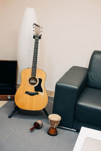 Guitar on sofa by table against wall at home