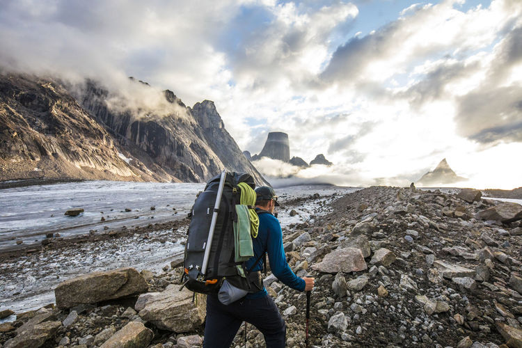 Rear view of backpacker approaching dramatic mountain summits, canada.