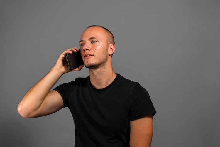 Young man using smart phone against gray background