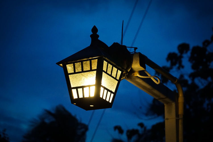 Low angle view of illuminated street light against blue sky