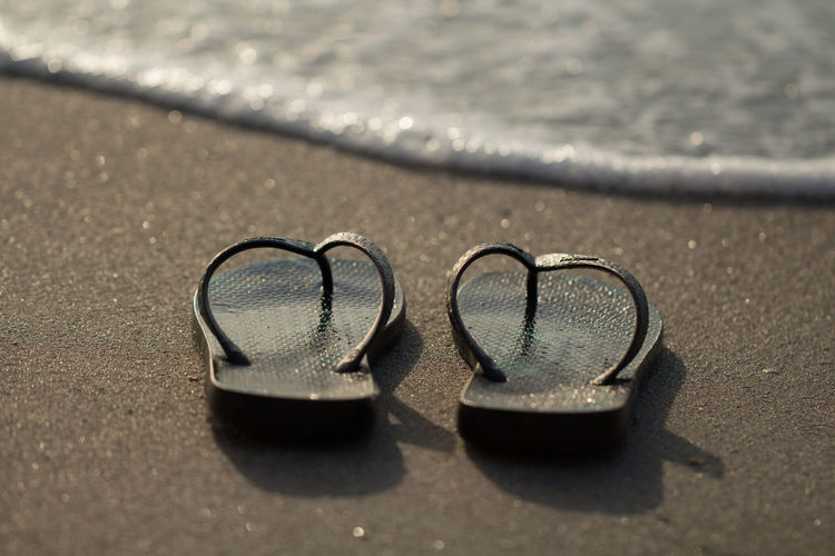 Close-up of shoes on beach
