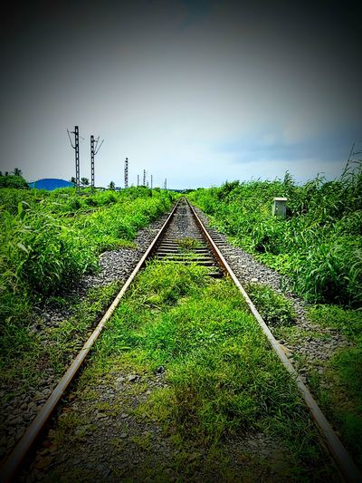 Railroad track amidst field against sky