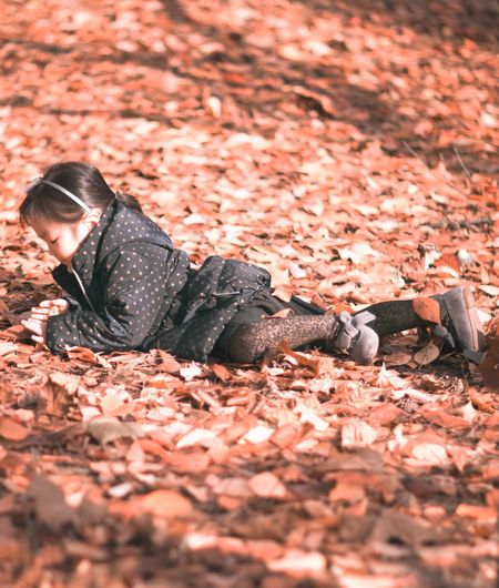 Girl lying on autumn leaves at field