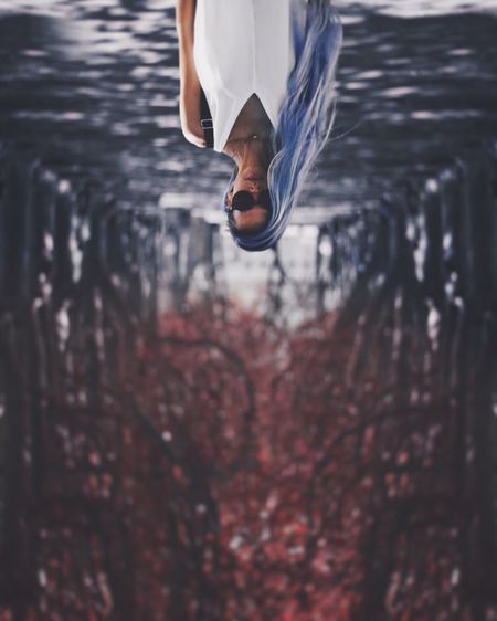 Upside down image of young woman with dyed hair standing on road