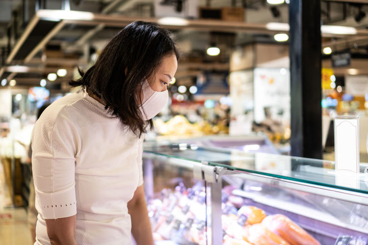 Young asian woman kid with face mask in supermarket. concept for life in outbreak and new normal.