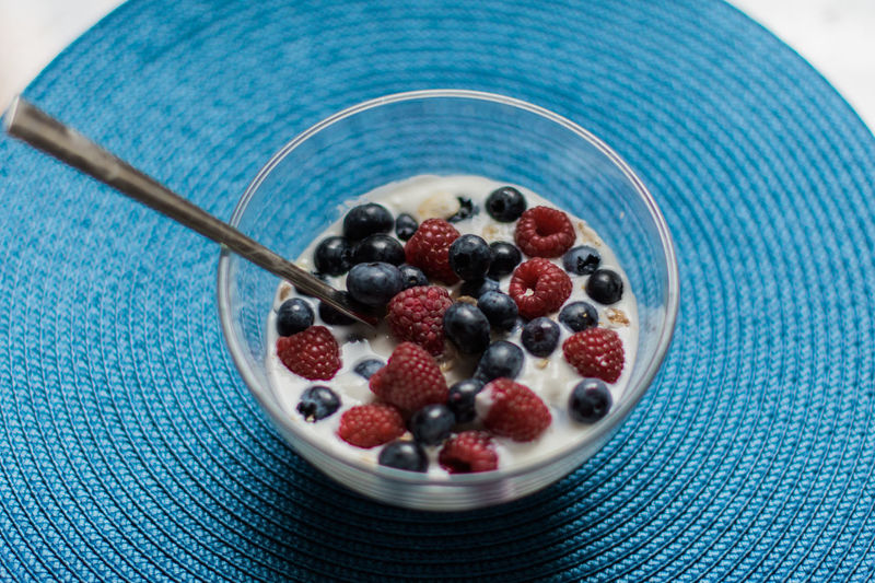 High angle view of fresh berries with yogurt in bowl on table
