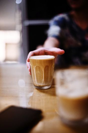 Hand holding coffee cup on table