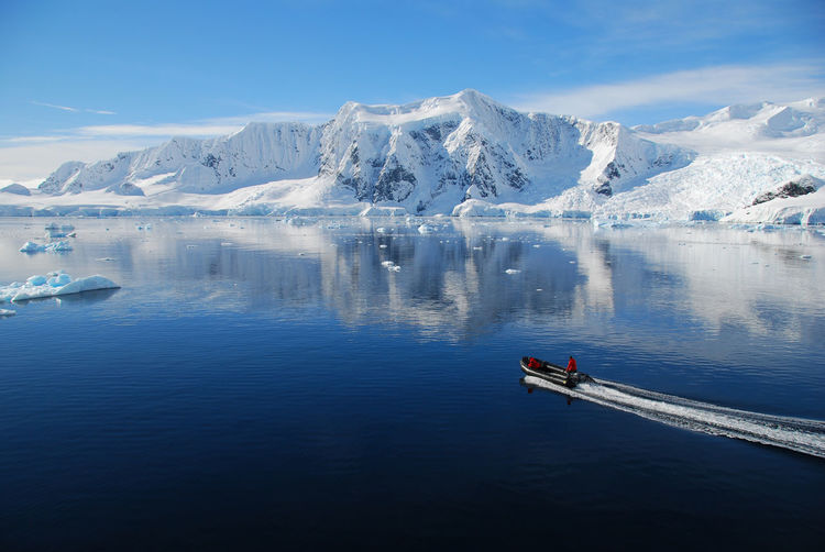 Scenic view of lake by snowcapped mountain against sky