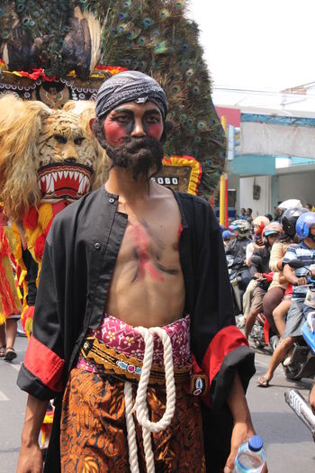 Man with face paint wearing costume on road during traditional festival