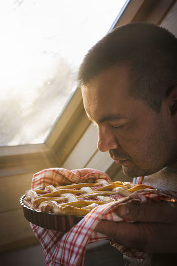 Close-up of man smelling food sitting at home
