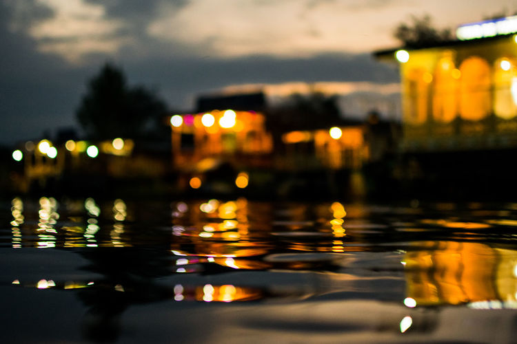 Reflection of illuminated buildings in water at sunset