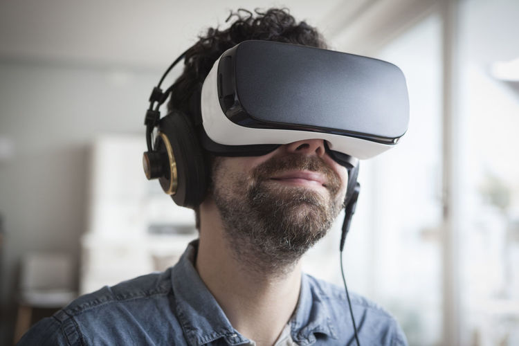 Smiling man wearing virtual reality glasses and headphones