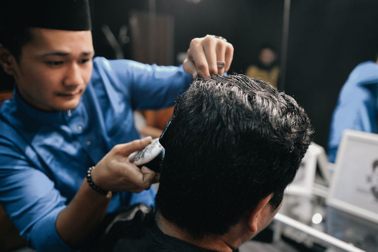 Hair dresser cutting hair of customer