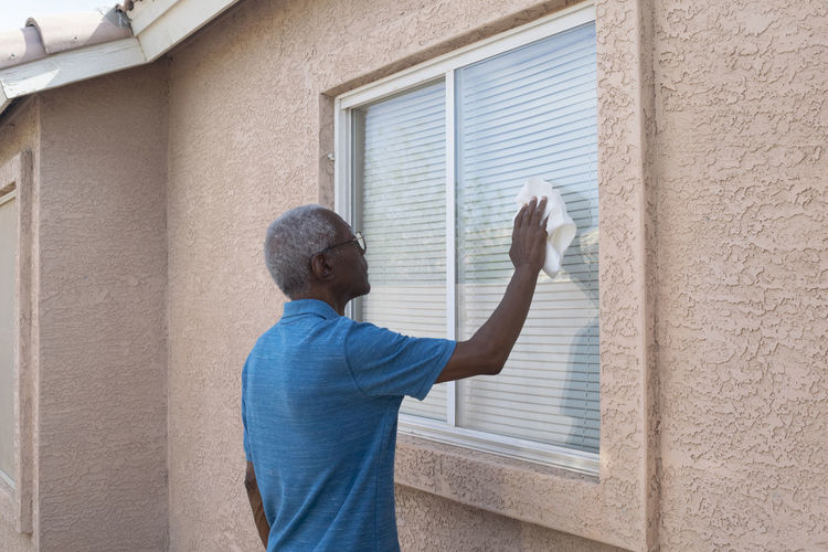 Rear view of man standing by window of building