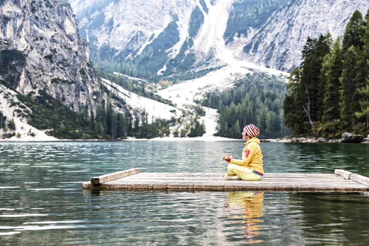 Man sitting on boat in lake against mountains