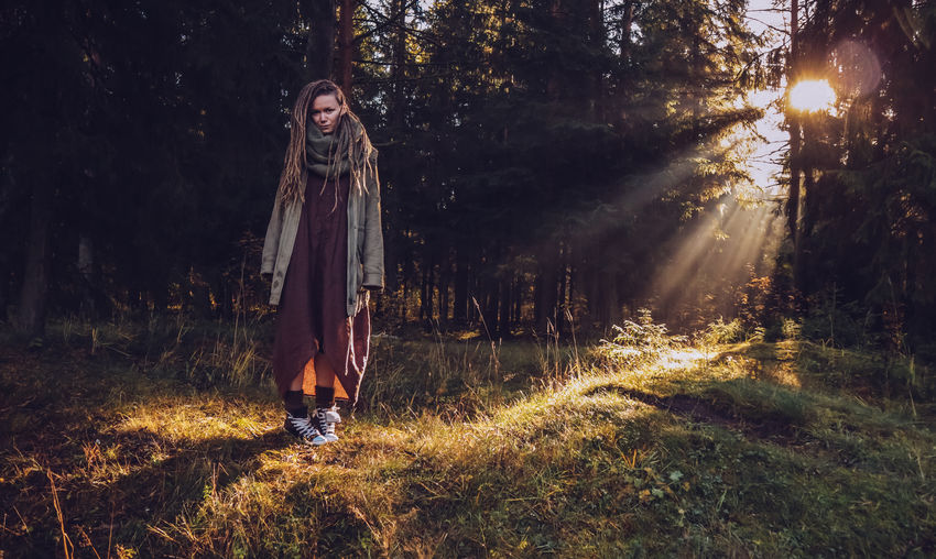 Full length of woman with dreadlocks standing in forest