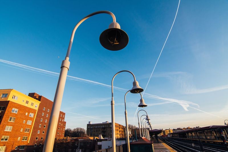 Low angle view of lighting equipment at railroad station against sky