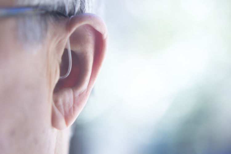 Close-up of man with hearing aid against blurred background