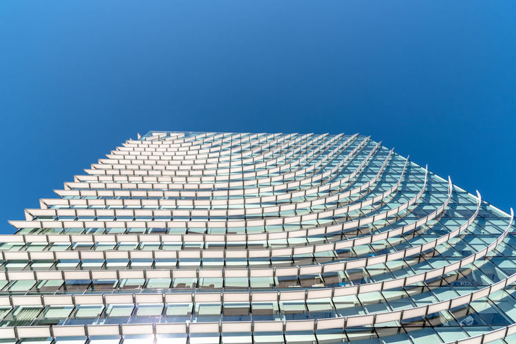 Low angle view of modern building against clear blue sky