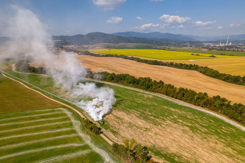 Aerial view of a tractor spreading lime on fields to improve soil quality after the harvest. 