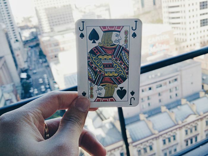 Cropped hand of person holding playing card on balcony in city