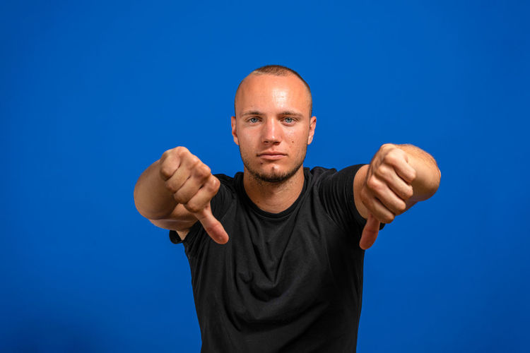 Portrait of man standing against blue background