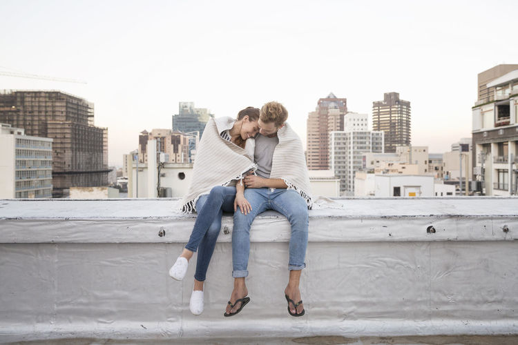 Romantic couple sitting on rooftop terrace, enjoying the view
