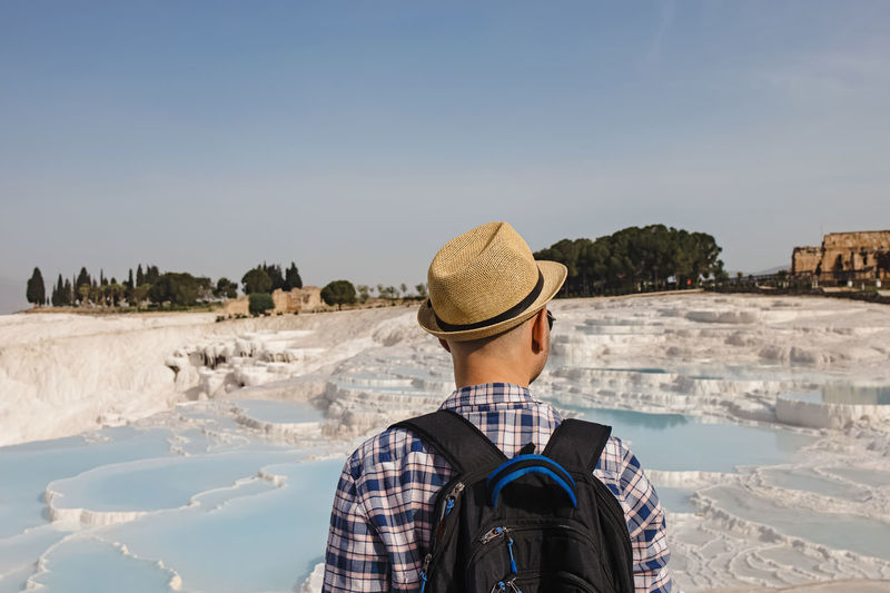 Young male tourist in straw hat looking to the natural travertine pools  in pamukkale, turkey