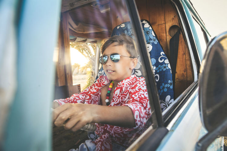 Boy wearing sunglasses driving car 