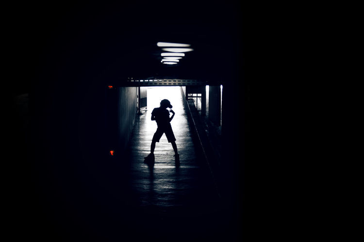 Silhouette woman walking in illuminated tunnel